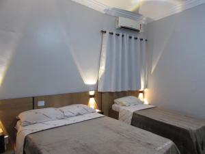 a bedroom with two beds and a window with lights at Hotel Tropicália próximo a 25 de março , Brás e Bom Retiro "Com estacionamento conveniado ao lado do hotel" in Sao Paulo