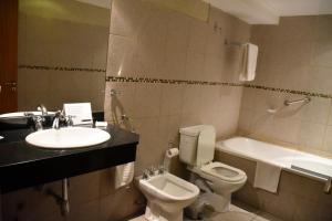 ein Badezimmer mit einem Waschbecken, einem WC und einer Badewanne in der Unterkunft Bahia Belgrano Suites in Bahía Blanca