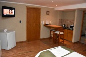a room with a kitchen and a television on the wall at Bahia Belgrano Suites in Bahía Blanca