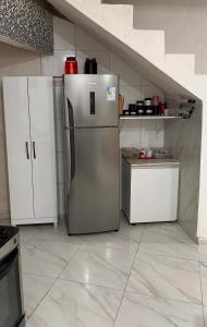 a kitchen with white cabinets and a stainless steel refrigerator at Casa na Ilha de Itamaraca in Vila Velha