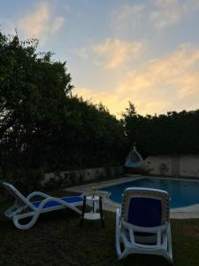zwei Stühle und ein Tisch neben einem Schwimmbecken in der Unterkunft Villa Grand residence Auc شارع ال 90 in Kairo