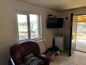 een woonkamer met een stoel en een televisie bij Cabana de la Sat in Iablaniţa