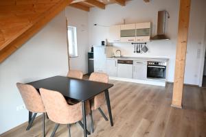 a kitchen and dining room with a black table and chairs at Ferienapartment bavarian living in Moosinning +15 photos