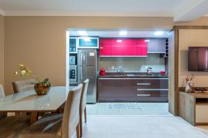 cocina con mesa y cocina con armarios rojos en Excelente no centro stayhousetemporada, en Canela 12 fotos más