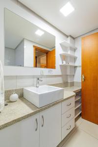Un baño blanco con lavabo y espejo. en Excelente no centro stayhousetemporada, en Canela