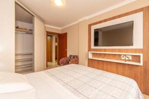 Un dormitorio con una cama y un televisor de pantalla plana. en Excelente no centro stayhousetemporada, en Canela