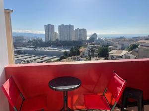 a red bench with a table and chairs in front of a window at DepartamentoSantaInes in Viña del Mar