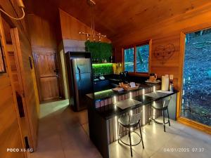 a kitchen with a black counter and a refrigerator at Janela do céu chalés in Maquiné