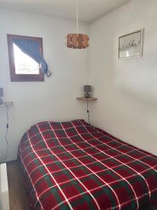 a bedroom with a bed with a plaid blanket at Appartement Arêches in Beaufort