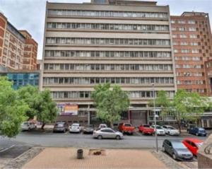 Un gran edificio con coches aparcados en un estacionamiento. en 50 stiemens street, en Johannesburgo