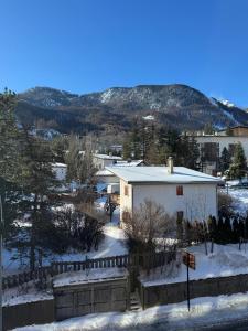 ein weißes Haus im Schnee mit Bergen im Hintergrund in der Unterkunft Studio cosy à 5 min à pied des pistes in La Salle Les Alpes