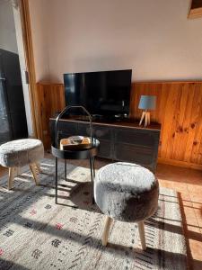 ein Wohnzimmer mit zwei Stühlen und einem Tisch und einem Fernseher in der Unterkunft Studio cosy à 5 min à pied des pistes in La Salle Les Alpes