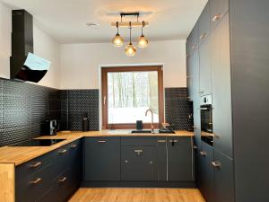 a kitchen with blue cabinets and a sink and a window at Domek w Górach Wilkanów Park in Wilkanów