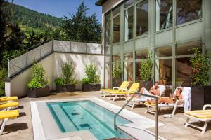 two people sitting in chairs next to a swimming pool at Familienhotel Sonngastein in Bad Gastein