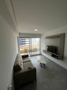 un soggiorno con un divano e una TV di APARTAMENTO EM CAMBOINHA PARA TEMPORADA EM JOÃO PESSOA, A 100M DO MAR E DE FRENTE A AREIA VERMELHAa a Cabedelo