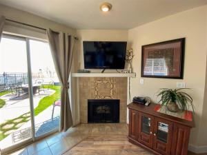 a living room with a fireplace with a tv above it at Inn Building Condo 103 updated, pool side view in Garden City