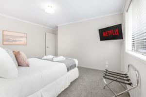 a white bedroom with a bed and a sign on the wall at Pool-Table, Projector, Fooseball -By KOSH BNB in Hamilton