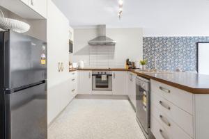 a kitchen with white cabinets and a stainless steel refrigerator at Pool-Table, Projector, Fooseball -By KOSH BNB in Hamilton