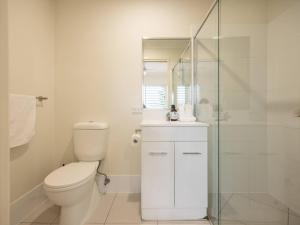 a white bathroom with a toilet and a glass shower at Walk to everything Modern 2Beds Apt with Easy Access in Springwood +2 photos