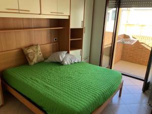 a bed with a green comforter in a room at Soffio di mare in Alba Adriatica