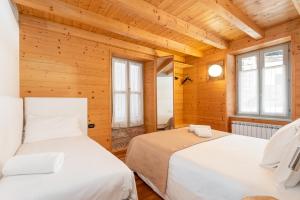 twee bedden in een kamer met houten wanden en ramen bij La Locandiera in Carona