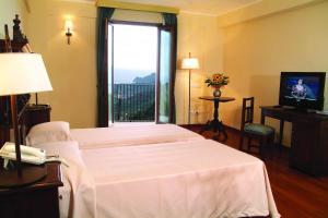 a hotel room with two beds and a television at Resort Borgo San Rocco in Savoca 