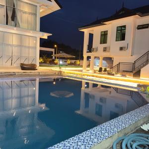 a swimming pool in front of a house at night at Homestay Miniwaterpark 1st klate in Kampong Kelewek
