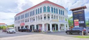 ein großes weißes Gebäude mit auf einem Parkplatz geparkten Autos in der Unterkunft welcome everyone in Ban Sam Kong