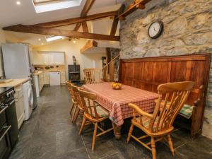 a kitchen with a table with chairs and a clock on the wall at Ysgubor in Machynlleth