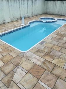 a swimming pool with a tiled floor and blue water at Casa da Praia in Osório