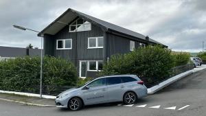 een kleine auto geparkeerd voor een huis bij Ingi's Guesthouse with a Car in Miðvágur