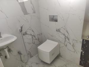 a white bathroom with a toilet and a sink at Bhoomi mansion Homestay Apartment 12 in Bhubaneshwar
