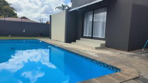 a house with a blue swimming pool next to a building at Trumma Guest House in Pretoria