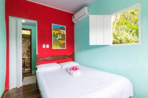 1 dormitorio con cama blanca y pared roja en SunriseBelaVista Pousada e Flats, en Paraty