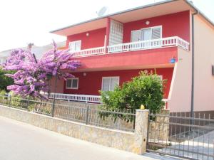 una casa rossa con una recinzione e fiori viola di Apartments Renko a Stari Grad (Cittavecchia)