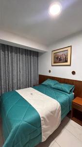 a bedroom with a green and white bed and a window at Hoteles Perla del Chira in Piura