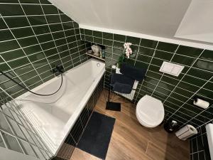 a bathroom with a tub and a toilet and green tiles at Ferienwohnung Gütersloh in Gütersloh +7 photos