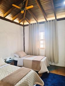 a bedroom with two beds and a ceiling fan at Pousada Mãe Terra in Torrinha