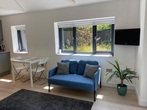 a living room with a blue couch and a table at The Garden Room in Henley on Thames
