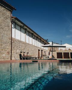 una piscina d'acqua di fronte a un edificio di Casa do Muro Alto a Alvelos