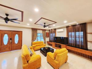 a living room with yellow chairs and a flat screen tv at ipoh 5min to town centre 92bungalow 5br5bath19pax in Ipoh