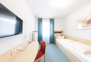 a hotel room with a bed and a flat screen tv at Hotel Central Hauptbahnhof in Heidelberg