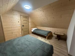 a small room with a bed in a wooden cabin at Zołcyniańsko Panorama in Załuczne