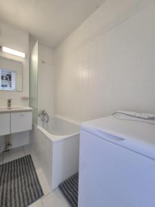 a white bathroom with a tub and a sink at Chez Laurette in Balaruc-les-Bains