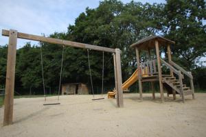 um parque infantil vazio com um escorrega e um baloiço em Camping La Pindière em Héric