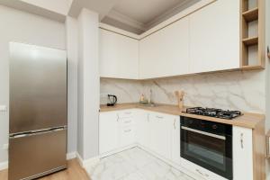 a kitchen with white cabinets and a stainless steel refrigerator at City Walk Apartment & MiRent in Chişinău