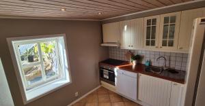 a kitchen with white cabinets and a window at Villa Thorse in Husvik