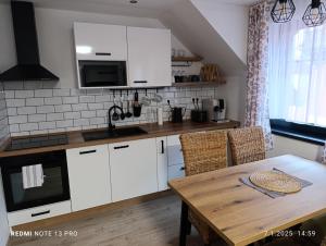 a kitchen with white cabinets and a wooden table at Apartmány Zdíkov in Zdíkov