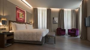 a hotel room with a large bed and two chairs at Fendi Private Suites in Rome