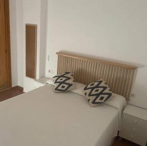 a white bed with two pillows on top of it at La Casa del Mar in Barbate